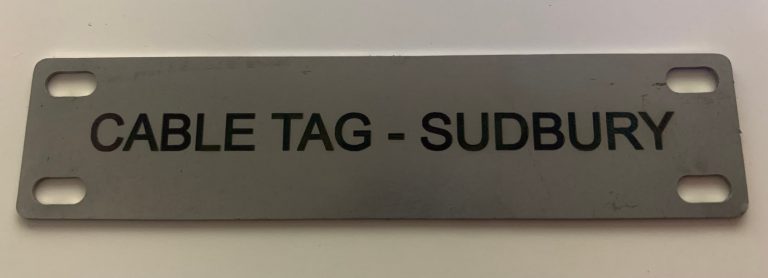 Laser-engraved 304 stainless steel cable tag reading CABLE TAG - SUDBURY, with four cable-tie slots